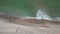 Aerial top view of sea waves hitting the beach with sea water.