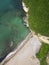 Aerial top view of sea waves hitting the beach with sea water.