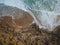 Aerial top view of sea waves hitting rocks on the beach with turquoise sea water. Amazing rock cliff seascape in the Portuguese co