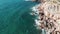 Aerial top view of stormy ocean waves hitting rocky shore. Drone shot of sea waves colliding with rocky cliffs. Water splashing an