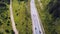 Aerial top view of summer green trees, river, roads in forest background. Aerial view of crooked path of road on the