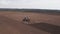 Aerial top view of tractor cutting furrows in farm field for sowing farm tractor with rotary harrow plow preparing land