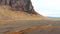 Aerial tracking panning view vehicle drive on Icelandic southern ring road with scenic mountains and wild landscape background