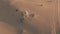 Aerial tracking shot of an unknown white SUV driving fast along sand dunes in the desert, UAE