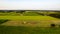 Aerial of tractor baler making straw bales in field after wheat harvest in summer on farm