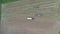 Aerial of tractor baler making straw bales in field after wheat harvest in summer on farm