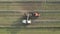 Aerial of tractor baler making straw bales in field after wheat harvest in summer on farm