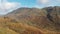 An aerial traveling footage of a beautiful mountain valley with rocky slopes, autumn colors and majestic blue