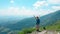 AERIAL: Unrecognizable young female trekker standing at the top of a mountain.