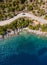 Aerial vertical shot of pickup truck moving by the curved road near sea tranquil waves on coast on Cephalonia Greek island.