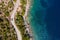 Aerial vertical shot of pickup truck moving by the curved road near sea tranquil waves on coast on Cephalonia Greek island.