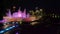 Aerial video of Musical fountain lit with purple light at night in the park