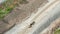 Aerial video on one heavy industrial yellow dump truck drives load of gravel on new highway road construction site, sunny day,