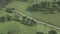 Aerial video of the road on the rural valley partly covered with trees