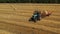 Aerial video. Rolling haystacks in countryside on the field on a cloudy day. Tractor loading hay bales on truck trailer