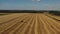 Aerial video. Rolling haystacks in countryside on the field on a cloudy day. Tractor loading hay bales on truck trailer