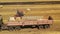 Aerial video. Rolling haystacks in countryside on the field on a cloudy day. Tractor loading hay bales on truck trailer