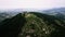 Aerial video of a white and red antenna tower on the mountain peak covered with forest