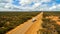 Aerial view of 4WD and modern caravan on an outback highway in Australia under a blue cloudy sky