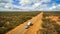 Aerial view of 4WD and modern caravan on an outback highway in Australia under a blue cloudy sky