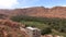 Aerial view of abandoned city with clay houses in Morocco with no people and green oasis with palm trees, red clay