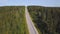 Aerial view from above of country road through the green summer forest in summer. Shot. Car driving. High angle view of