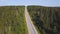 Aerial view from above of country road through the green summer forest in summer. Shot. Car driving. High angle view of
