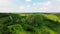 Aerial view from above on the country road in mountain range in between green grass and trees around