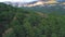 Aerial view above endless wide beautiful dense forest and the cloudy mountain on the horizon. Shot. Natural landscape