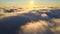 Aerial view from above at high altitude of dense puffy cumulus clouds flying in evening. Amazing sunset from airplane