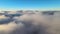 Aerial view from above at high altitude of dense puffy cumulus clouds flying in evening. Amazing sunset from airplane