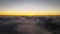 Aerial view from above at high altitude of dense puffy cumulus clouds flying in evening. Amazing sunset from airplane