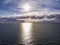 Aerial view above ocean, with  cloudy pastel colored scenic sky and  sun rays hits the water in a hot summer day