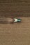 Aerial view of agricultural tractor tilling and harrowing ploughed field, directly above drone pov