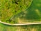 Aerial view of agriculture fields, meadow and road inside. Rural scene of countryside. Fresh green colors, look to above tree. Day