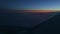 Aerial view from aircraft window across steel wing silhouette at dark sunset sky