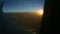 Aerial view from aircraft window across steel wing silhouette at summer sunset
