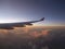 Aerial view from airplane, seeing plane`s wing and pink sunset light from left side