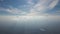 Aerial view from airplane window at high altitude of distant city covered with layer of thin misty smog and distant clouds.