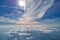 Aerial view from airplane window at high altitude of earth covered with white thin layer of misty haze and distant clouds