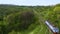 Aerial view on alone electric train locomotive moving on railroad through the foresty hills