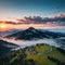 Aerial view of alpine meadows and mountains in low clouds at amazing sunrise in summer. Top drone view of