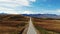 Aerial view of amazing road with view of the Caucasian ridge and Mount Elbrus. Highway runs through green meadow. Light