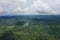 Aerial view of the Amazon with a large brown river meandering through the landscape and shadows of clouds over the rainforest