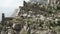 Aerial view of an ancient abandoned stone village with ruined buildings. Action. Rock cliff with old towers and