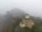 Aerial view of ancient Christian Sentinel Church, Caucasus. It is located on spur of mountain range. Thick fog covers