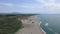 aerial view as the drone soars over a secluded beach with black sand and powerful waves crashing against the shore