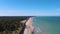 Aerial view ascending along Latvian Baltic sea seaside beach coast revealing wind turbine near Liepaja