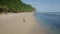 Aerial view athlete runs alone on sandy beach, ocean and mountains on background