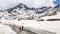 An aerial view of an attractive group of people riding bikes on a road in the mountain view with snow in Dolomite Mountains